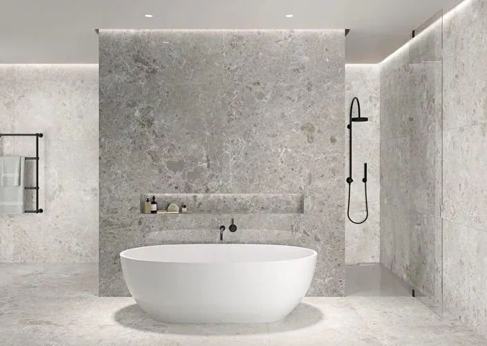 Bagno moderno con piastrelle effetto pietra Artic di Grespania, vasca freestanding e doccia minimal.